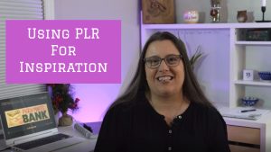 Image of a middle aged woman with brown hair in a black shirt sitting at a desk. The words "Using PLR for Inspiration" are written on the screen in white letters on a pink background.